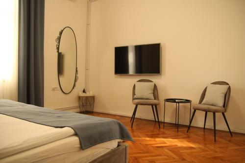 贝尔格莱德Natalie's Royal M的卧室配有两把椅子和墙上的电视。