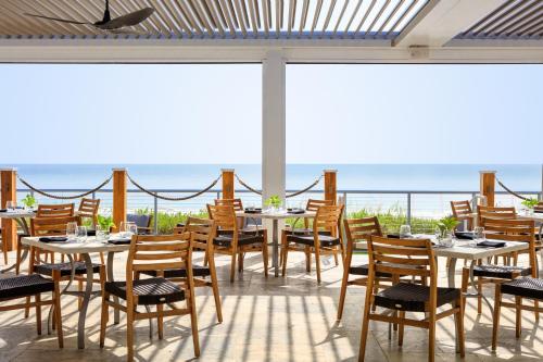 维洛海滩金普顿维罗海滩Spa酒店 的餐厅设有桌椅,以大海为背景