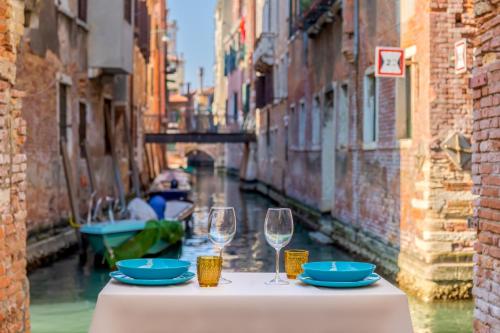 威尼斯Ramo del teatro Canal view的一张桌子,配有两杯酒,享有运河的景色