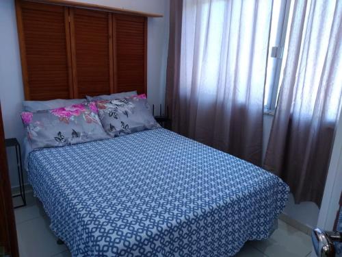 尼泰罗伊Loft Aconchegante no Centro de Niterói!的一间卧室配有一张带蓝色和白色棉被的床