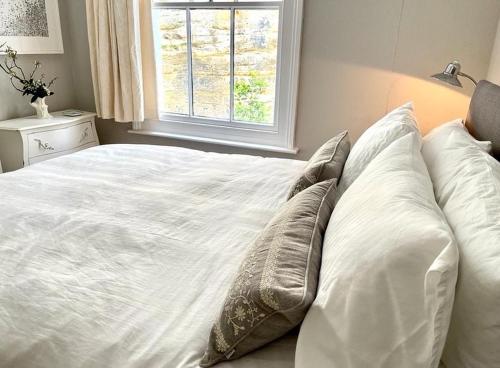 海斯廷斯Gloucester House的卧室配有带枕头的白色床和窗户