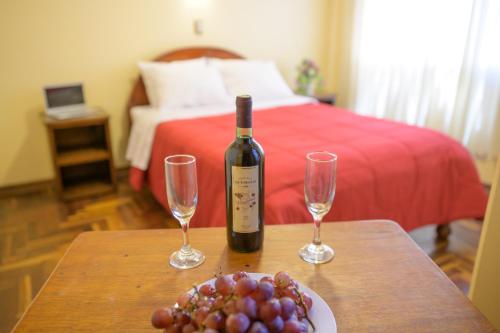 普诺Hostel Sol Andina Inn的桌子上一瓶葡萄酒和两杯酒