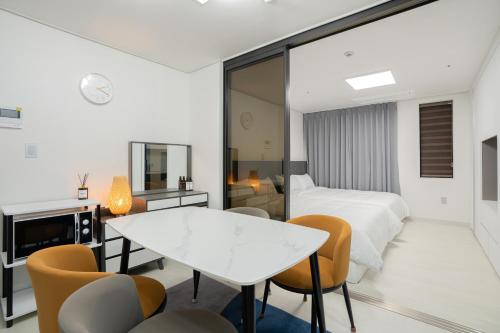 济州市Jeju Seomun Residence Hotel的卧室配有一张床和一张桌子及椅子