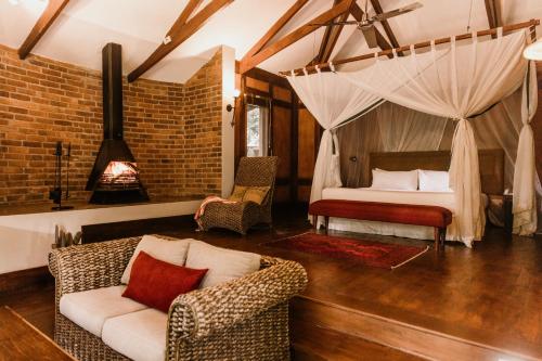 阿鲁沙Elewana Arusha Coffee Lodge的一间卧室配有一张床、一张沙发和椅子