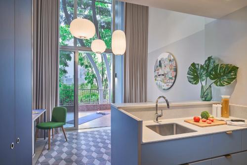 新加坡Citadines Raffles Place Singapore的厨房配有水槽、桌子和窗户