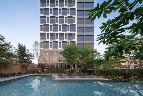 曼谷Ramada By Wyndham Bangkok Sukhumvit 87的一座高楼前的游泳池