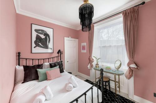 巴斯Stylish Georgian Apartment near the centre of Bath的卧室设有粉红色的墙壁、一张床和窗户