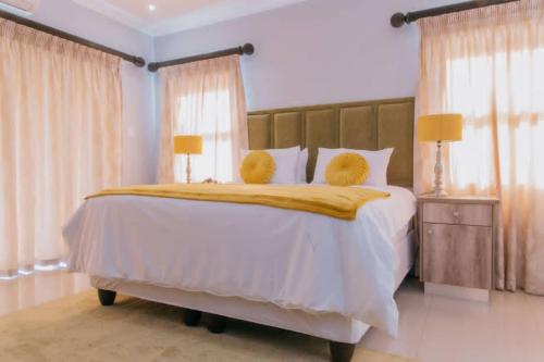 埃祖尔韦尼Mantenga Hillview的卧室配有一张带两个黄色枕头的大型白色床