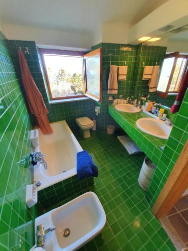 Villa Tramonti di Gallura的绿色瓷砖浴室设有两个盥洗盆和一个浴缸