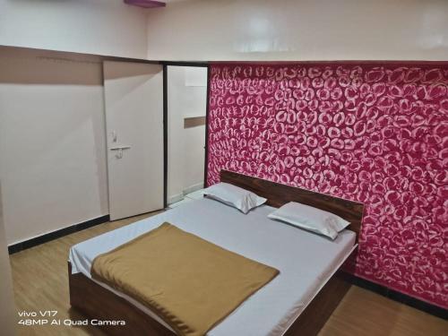 舍地Sai Ganesh Guest House的一间卧室配有一张红色墙壁的床