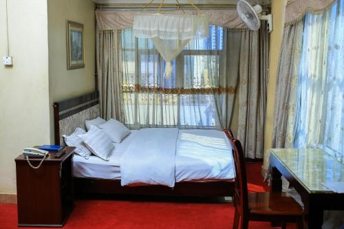 坎帕拉Steric Hotel Kampala的一间卧室配有一张带窗户和桌子的床
