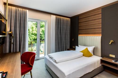 奥利希Hotel Am Schloss Aurich - Schlossresidenz的酒店客房,配有一张床和一张红色椅子