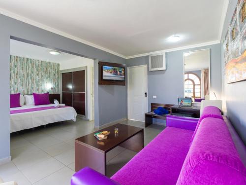马斯帕洛马斯厄沃金色花园套房酒店的客厅配有紫色沙发和床。