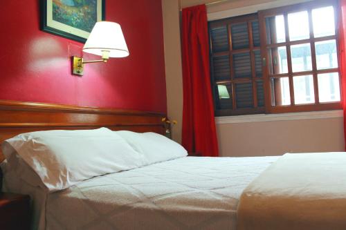 布宜诺斯艾利斯锦绣酒店的一间卧室设有一张床和红色的墙壁