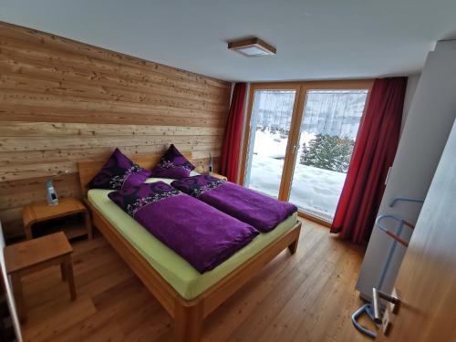 利德阿尔卑斯Chalet Enzian的一间卧室配有一张带紫色床单的床和窗户。
