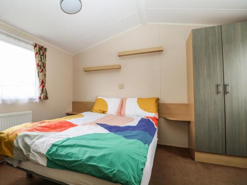 南安普敦Solent Breezes, Caravan 108的一间卧室配有一张带彩色毯子的床