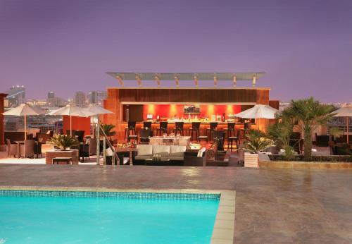 迪拜媒体路特娜酒店的一座带餐厅的建筑屋顶上的游泳池
