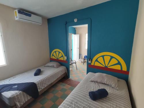 韦拉克鲁斯Chuchumbé Hotel & Hostal的两张床位于带蓝色和黄色墙壁的客房