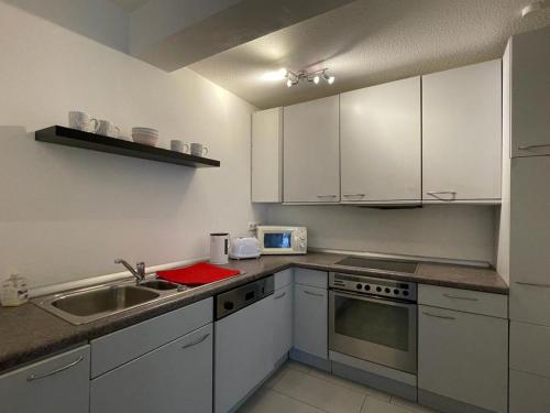 格拉德贝克Modernes Appartement的厨房配有白色橱柜和水槽