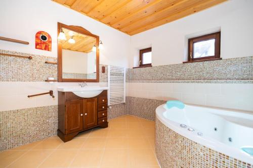 KordíkyOčarujúci drevený dom v prírodnom prostredí的带浴缸、水槽和镜子的浴室