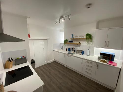 法尔茅斯Bank Place的白色的大厨房配有白色橱柜和木地板