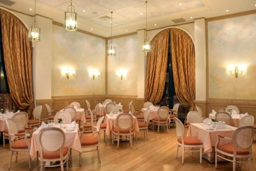 沃洛斯沃洛斯宫殿酒店的用餐室配有桌椅和吊灯。