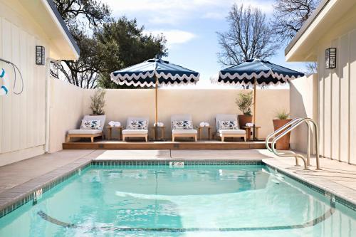 索尔万Hotel Ynez的房屋旁的游泳池配有椅子和遮阳伞