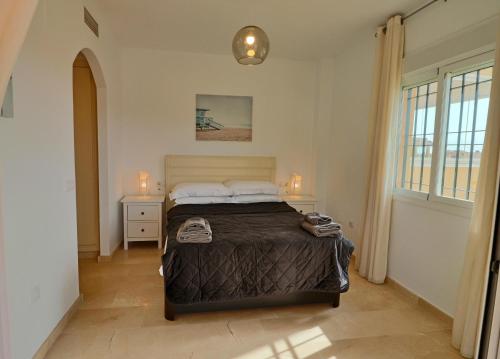 米哈斯科斯塔La Mirada的一间卧室设有床、两张桌子和一扇窗户