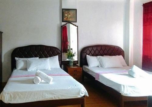 KabankalanRedDoorz at RHR Tourist Inn Canlaon的配有白色床单的酒店客房内的两张床