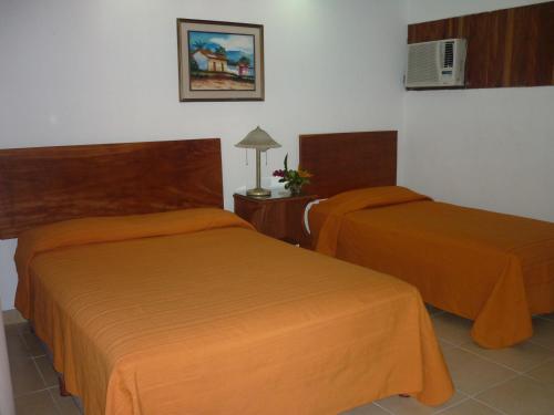 利比里亚布拉马德罗酒店的配有橙色床单的酒店客房内的两张床