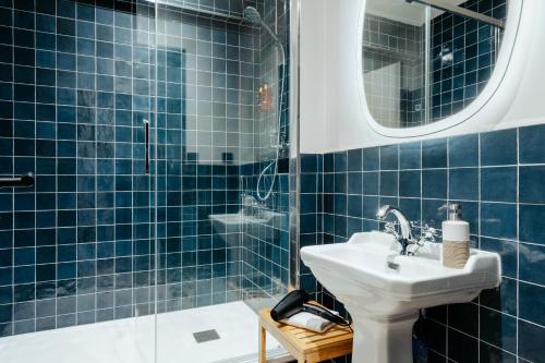 巴黎Edgar Suites Montmartre - Abbesses的蓝色瓷砖浴室设有水槽和淋浴