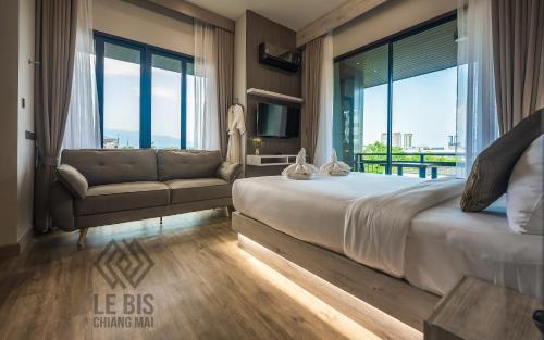 清迈Le Bis Hotel的一间卧室配有一张床、一张沙发和窗户。
