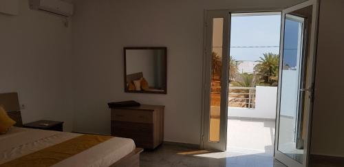 米多恩Villa Aline Lagune Djerba的一间带床和镜子的卧室以及一个阳台