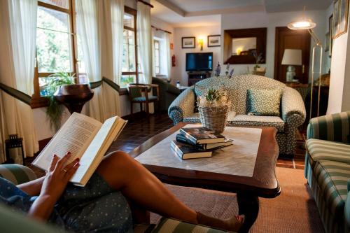 奥耶多Hotel Infantado的女人在客厅的咖啡桌上读书