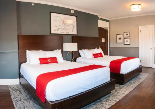 格伦斯福尔斯昆斯伯里酒店的两张位于酒店客房的床铺,配有红色枕头