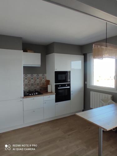 库尔瑟勒·苏尔·梅尔appartement belle vue的厨房配有白色橱柜和黑微波炉