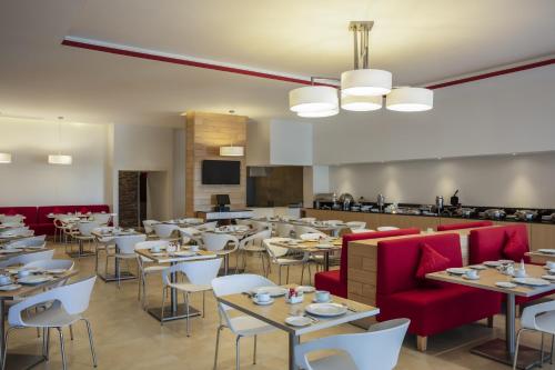 塞拉亚Fiesta Inn Celaya Galerias的用餐室配有桌子和红色椅子