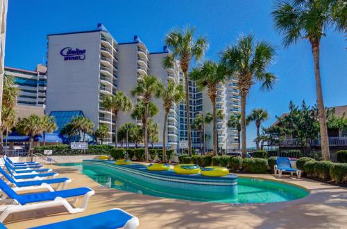 默特尔比奇Carolina Winds的一个带躺椅和棕榈树的游泳池的度假酒店