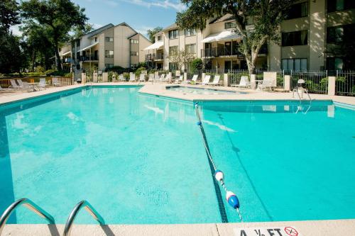 希尔顿黑德岛Springwood Villas II的一个带椅子和公寓的大型蓝色游泳池