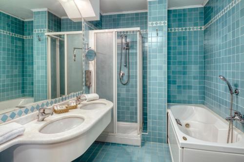 特雷维索卡尔顿酒店的蓝色瓷砖浴室设有水槽和浴缸