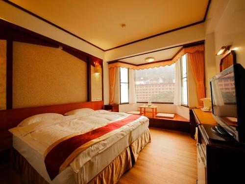和平区神木谷假期大饭店的一间卧室配有一张大床和电视