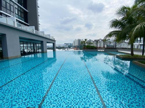 吉隆坡Lily and Loft - Queensville @ Kuala Lumpur - Netflix的一座种植了棕榈树的大型蓝色游泳池和一座建筑