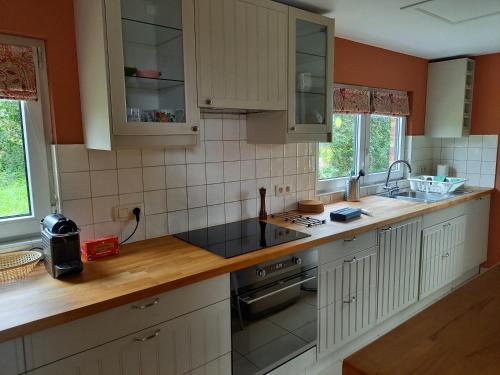 罗什福尔Jamblinne 43的厨房配有白色橱柜和木制台面