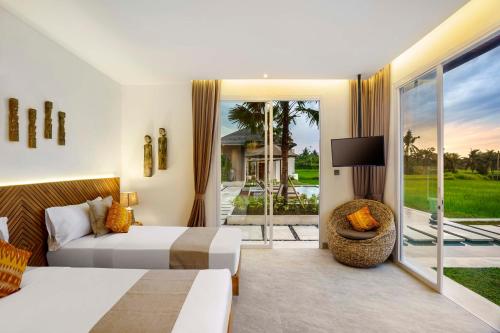 乌布Villa So'Cocoon的一间卧室设有一张床、一台电视和一个阳台。