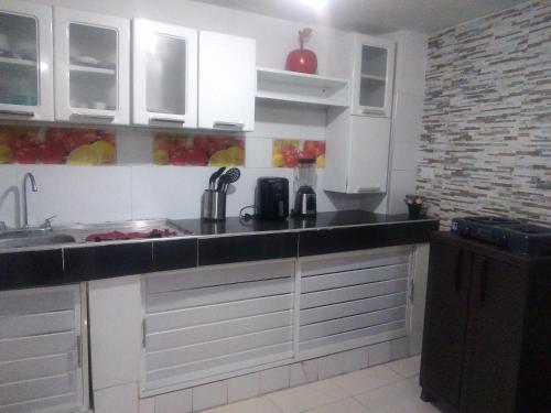 巴兰基亚Encantadora casa con ambiente guajiro 2的厨房配有白色橱柜和黑色台面