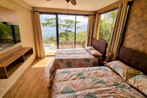 查梅Cabaña con Espectacular Vista a las Montañas的带大窗户的客房内的两张床