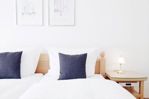 LöningenHotel Restaurant Rüwe的卧室内配有两张带蓝色枕头的白色床。