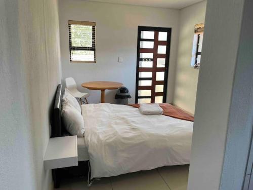 SandtonPrivate and cozy的一间卧室配有一张床、一张桌子和一个窗户。