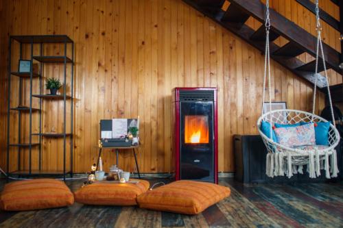 科瓦斯纳The Wooden Nest -Covasna的客房设有带壁炉和橙色枕头的木墙。