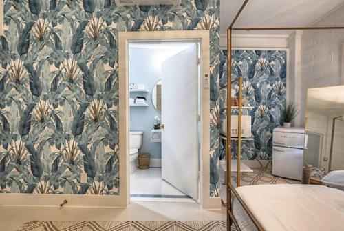 加尔维斯敦The Oleander Hotel Room 5的一间卧室,浴室内装饰有热带壁纸